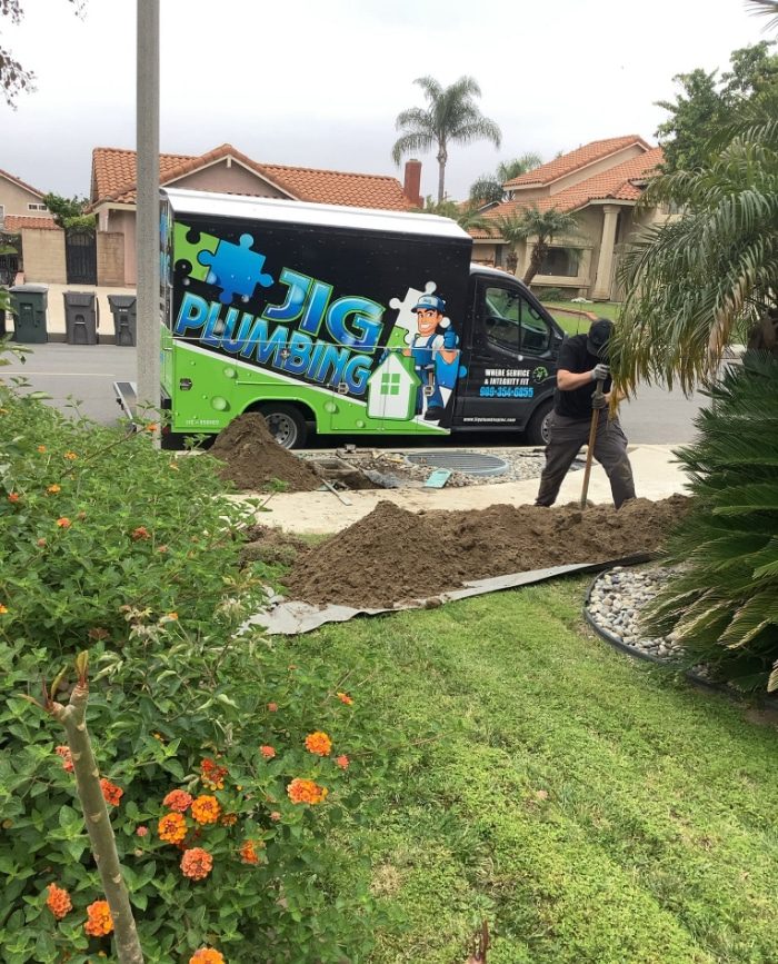 JIG Plumbing van and employee replacing water line in Chino, California yard